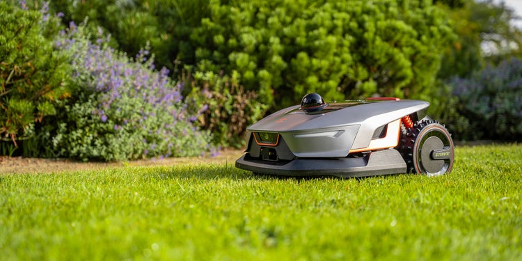 Foto eines sunseeker Mähroboters X4 auf Rasen neben einem Blumenbeet