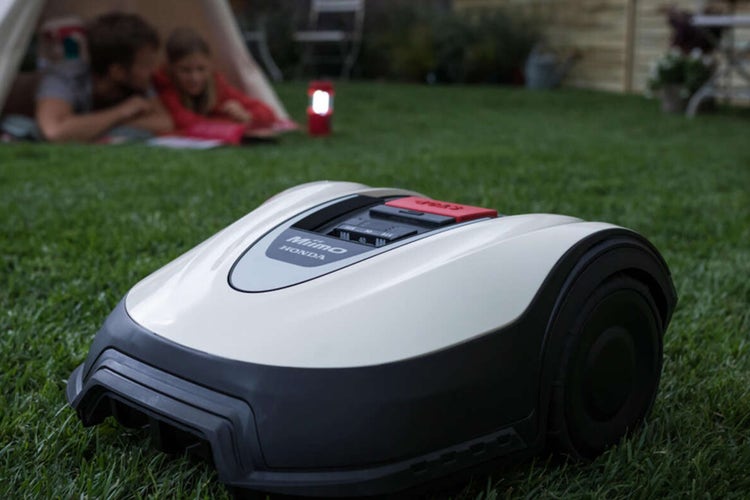 HONDA MiiMo fährt vor einem Zelt im Garten vorbei
