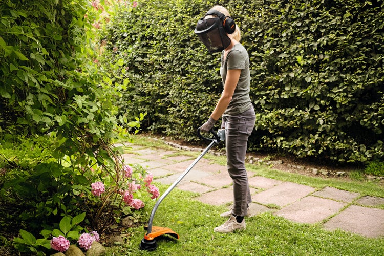 Eine Frau trimmt ihren Rasen mit dem STIHL Freischneider FS 38