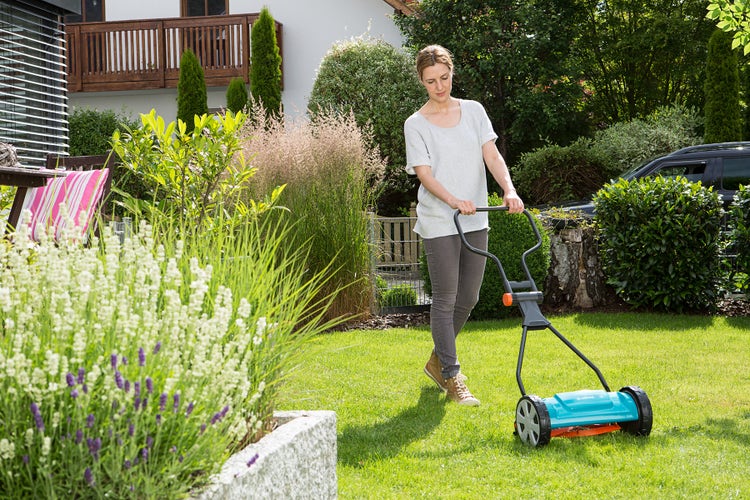Eine Frau mäht ihren Rasen mit dem GARDENA Spindelmäher Classic 330