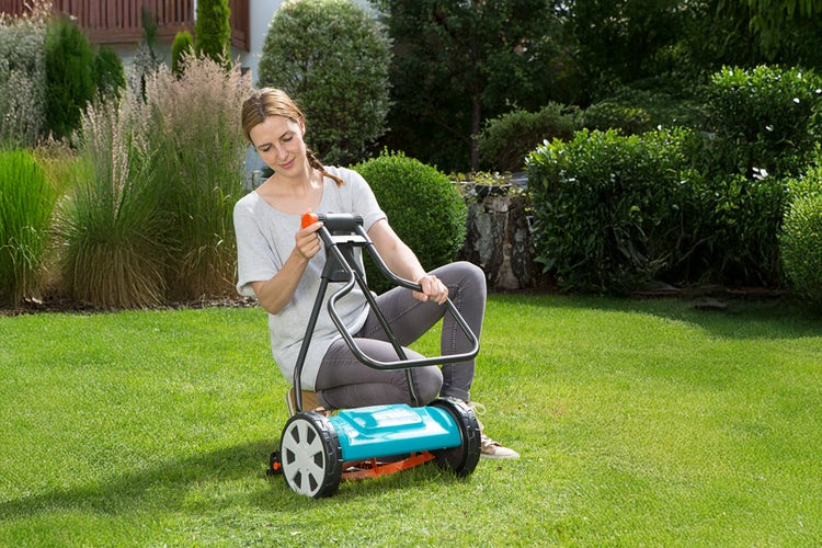 Eine Frau klappt ihren GARDENA Spindelmäher Classic 330 zusammen