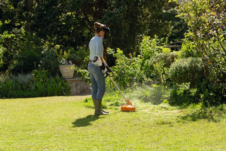 Frau trimmt mit STIHL FSA 60 Akku-Freischneider