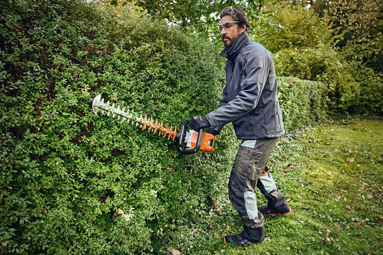 Mann schneidet Hecke mit Stihl HSA 100 Heckenschere
