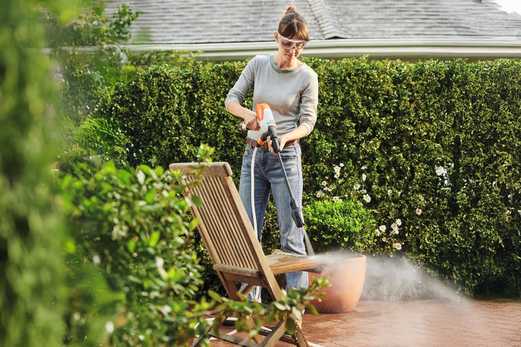 Eine Frau reinigt einen Gartenstuhl mit dem STIHL RCA 20