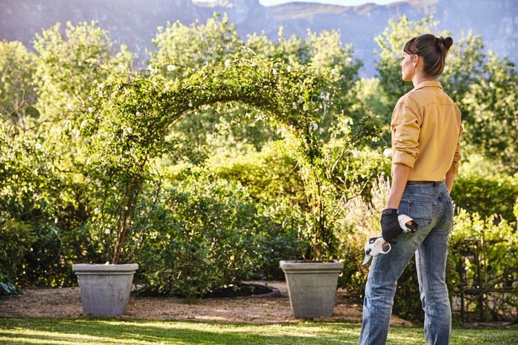 Eine Frau steht im Garten mit der STIHL ASA 20 in der Hand