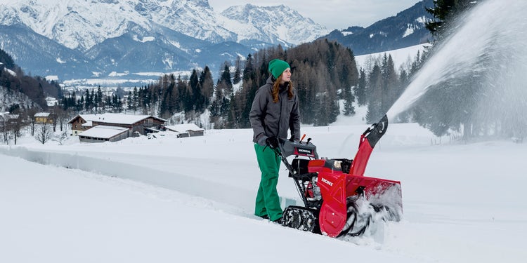 Frau mit Schneefräse von Honda am arbeiten im tiefen Schnee
