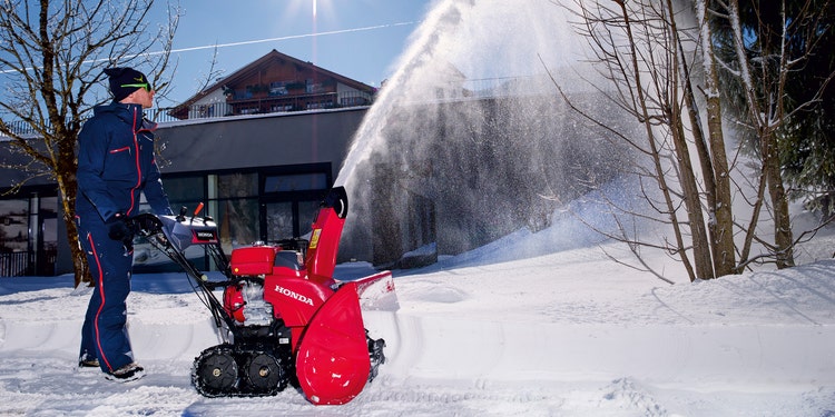 Mann im Einsatz mit Honda HSS 1380i1 TD HYBRID Schneefräse